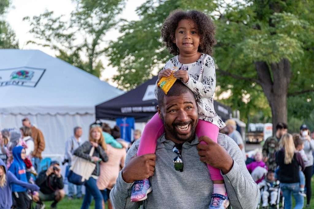 girl sitting on smiling man s shoulder